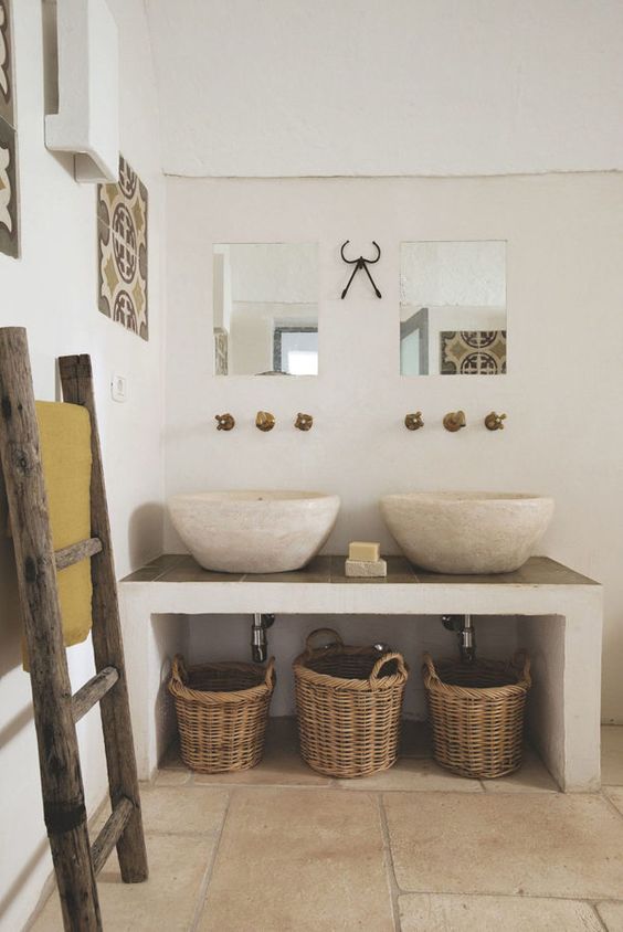 bagno rustico estivo con lavandini in travertino e cesti di paglia